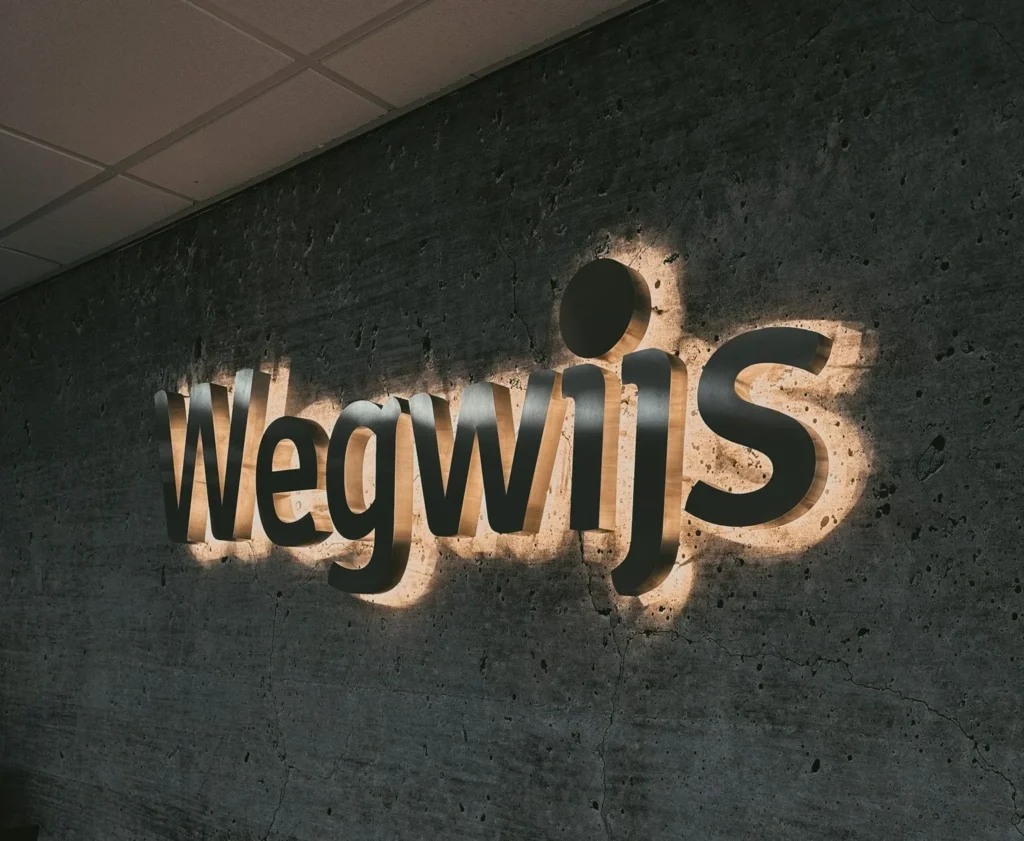 Verlicht Wegwijs-logo op de wand van het kantoor in Den Haag
